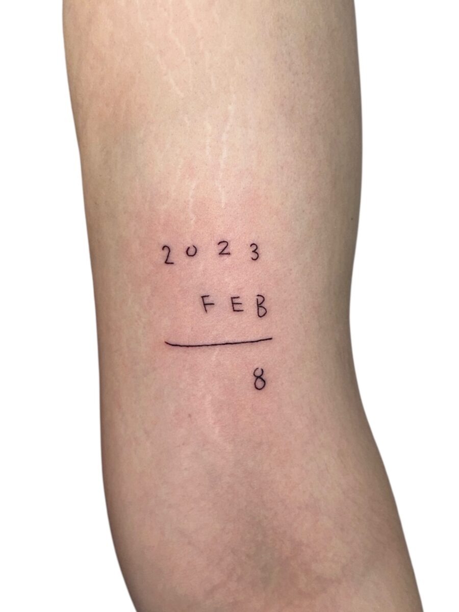This tattoo showcases the date '2023-FEB-8' in a sleek, minimalist style.
