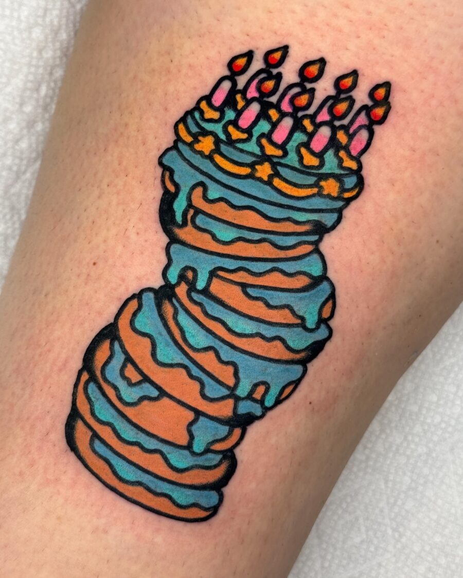 This playful tattoo features a stack of colorful birthday cakes adorned with candles.