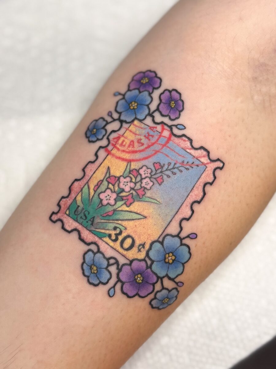This unique tattoo showcases a vintage stamp design adorned with delicate flowers.