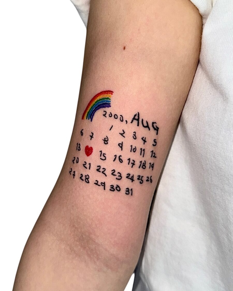 This tattoo features a rainbow above a unique calendar design.