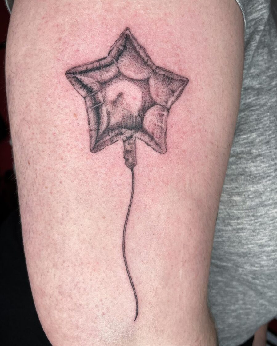 This tattoo features a stunningly realistic star-shaped balloon, creating a nostalgic vibe.
