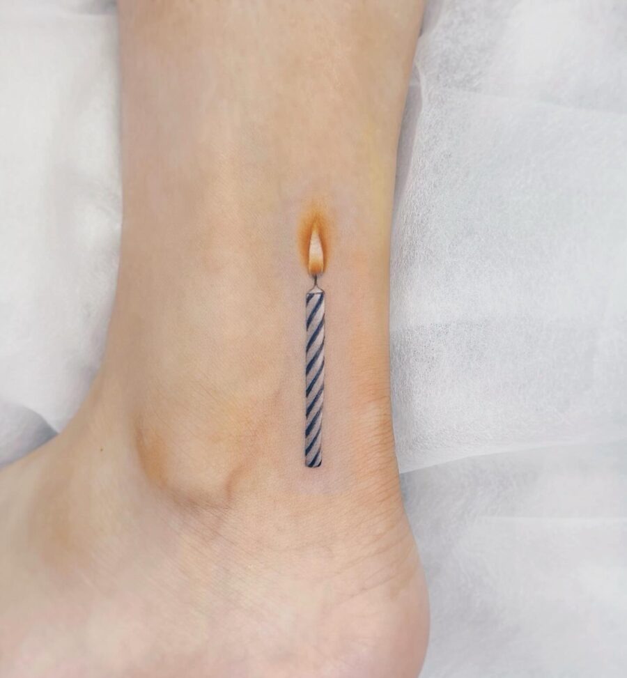 This tattoo features a beautifully designed candle with a twist, elegantly placed on the ankle.