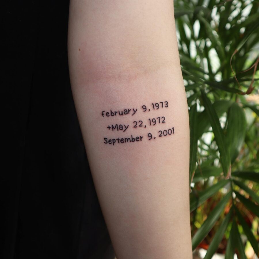 This tattoo features three important dates in a clean, understated font.