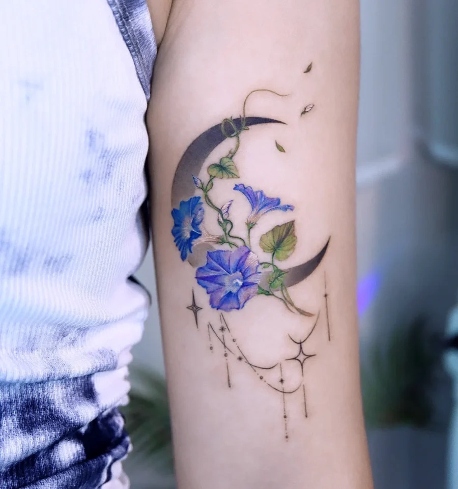 This beautiful tattoo features blue flowers intertwining with crescent moons.