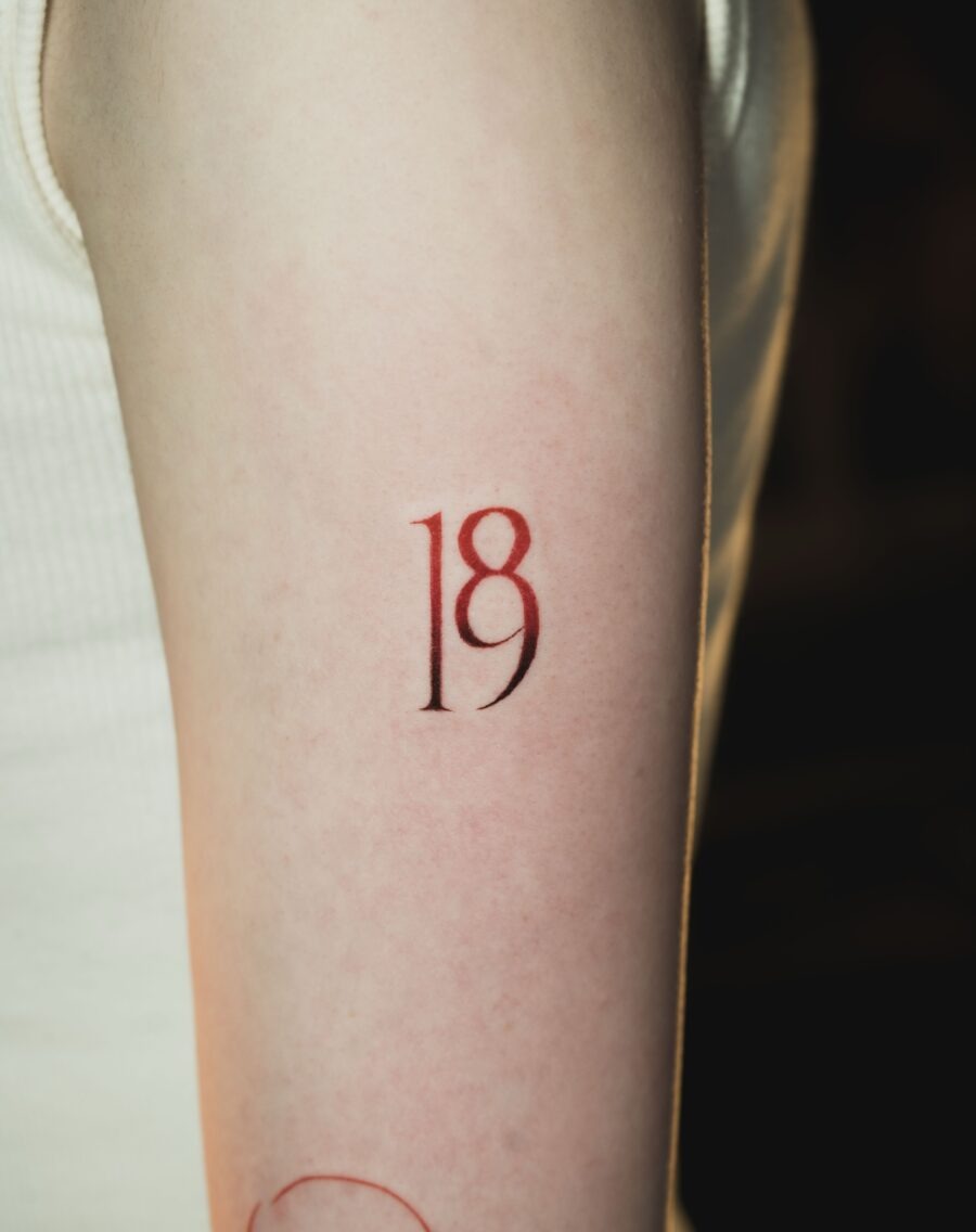 This tattoo features a bold '18' in a striking red hue, perfect for celebrating coming-of-age milestones.