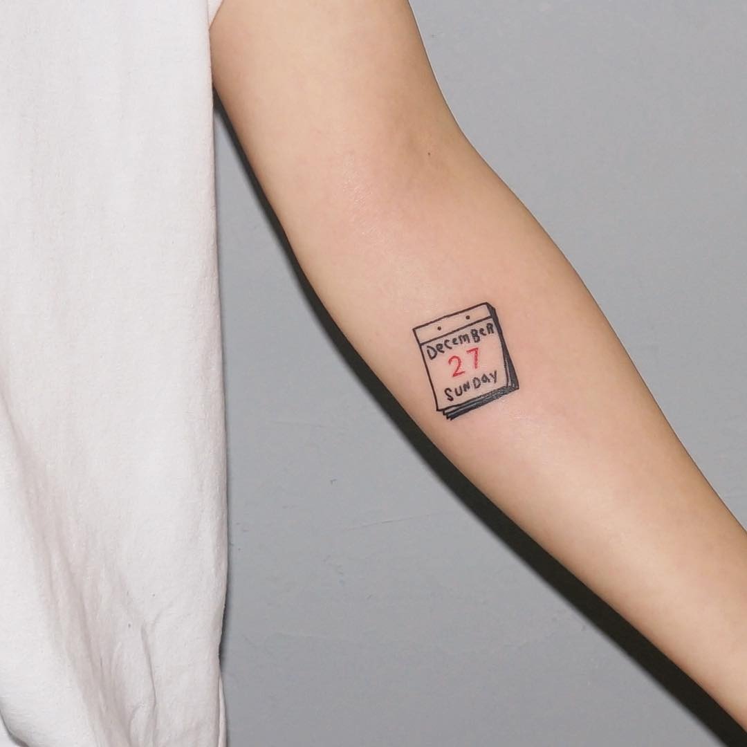 This tattoo features a simple calendar design marking a special date.