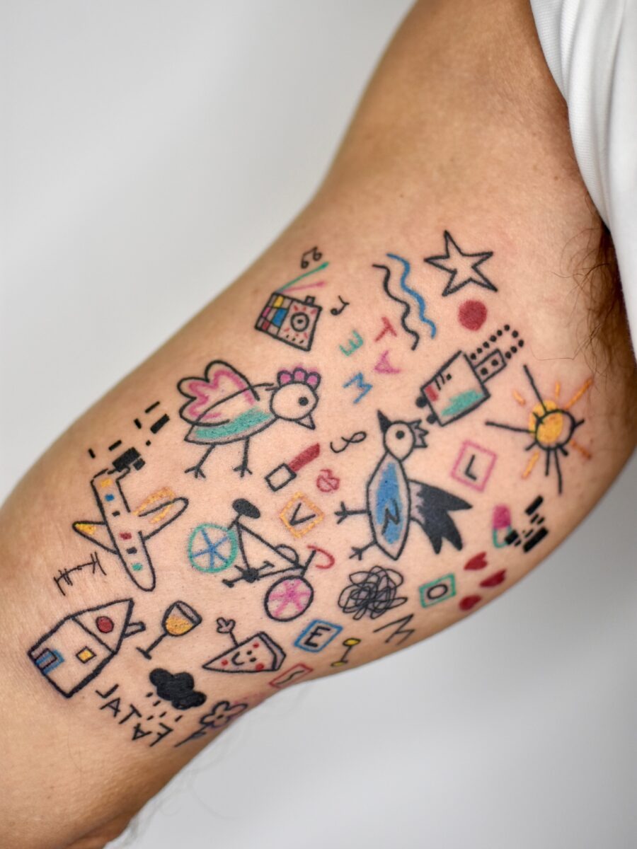 This tattoo features colorful and whimsical birthday motifs, ranging from playful birds to cheerful suns.