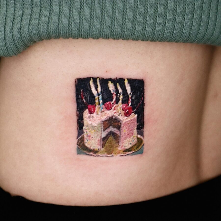 This colorful cake tattoo showcases a delicious slice decorated with cherries and candles.