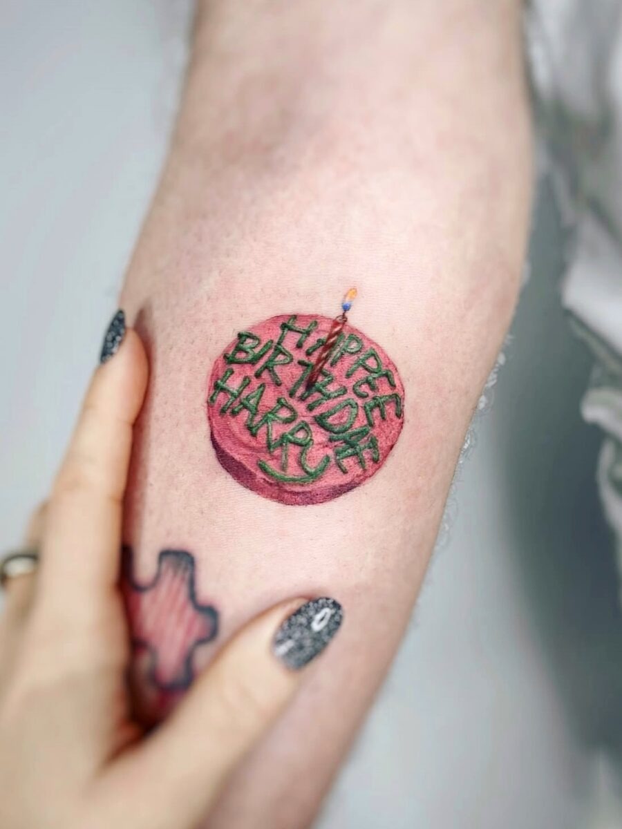 This tattoo features a charming birthday cake complete with colors that pop.