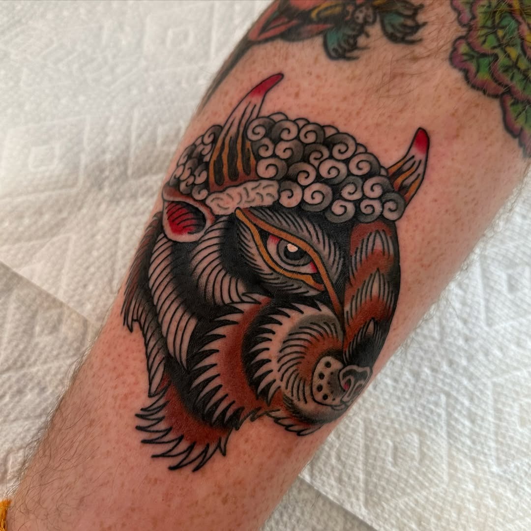 This bison tattoo features colors and bold lines, showing a fierce expression.