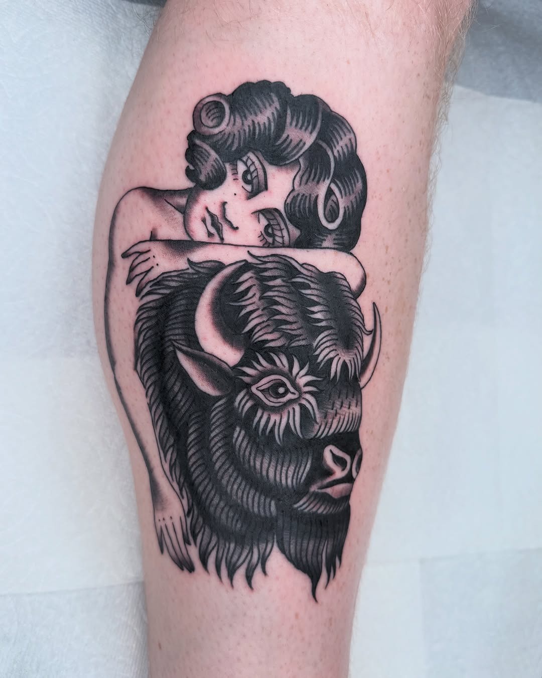 This bison tattoo features a charming juxtaposition of a girl resting on the majestic animal's back.