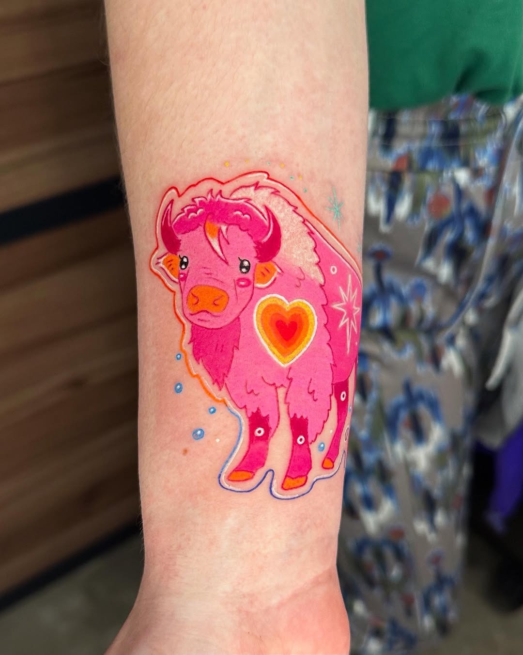 This colorful bison tattoo features bright pink hues and charming heart accents.