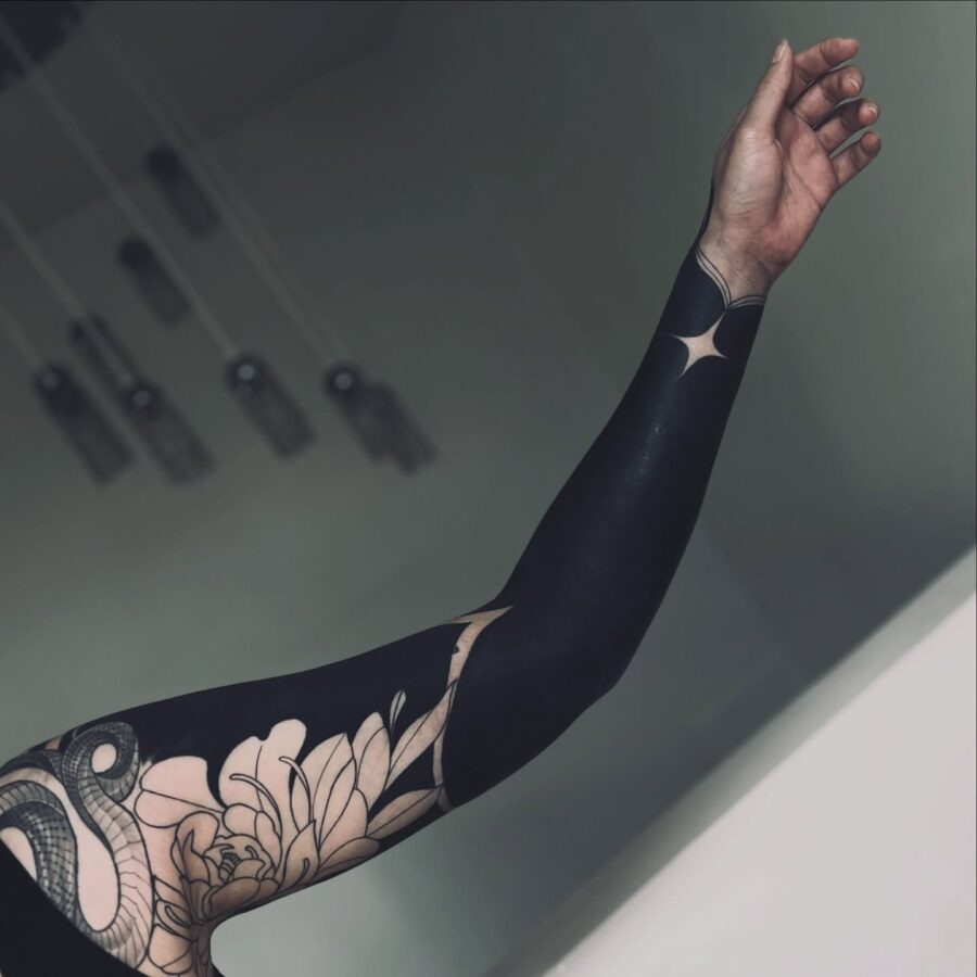 This black sleeve tattoo features a stunning blend of floral designs and geometric shapes, creating an eye-catching visual impact.