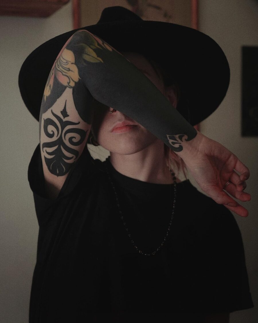 This image showcases a striking black sleeve tattoo adorned with intricate designs.