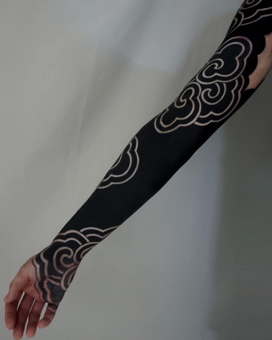 This stunning black sleeve tattoo features intricate cloud patterns in a deep black shade with contrasting outlines.