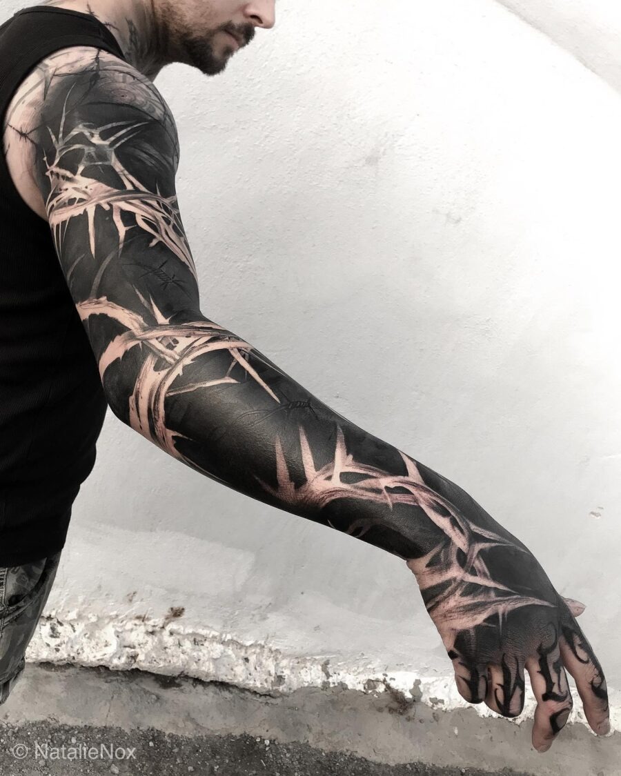 This tattoo features intricate black bamboo elements that wrap around the arm.