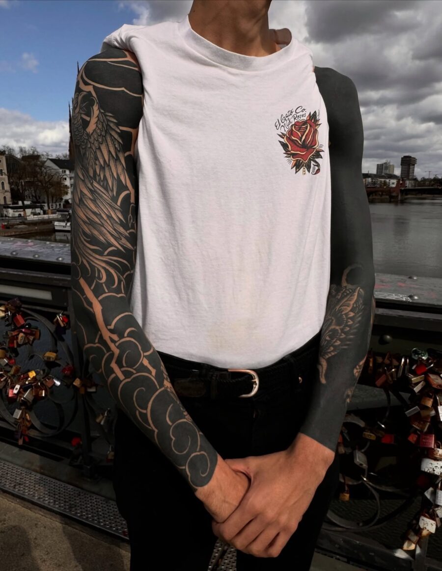 This image features a striking black sleeve tattoo that beautifully intertwines artistic elements.