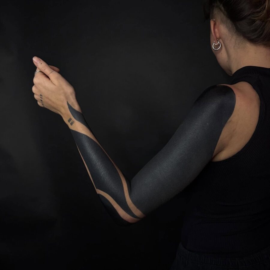 This black sleeve tattoo features bold, abstract designs that flow seamlessly over the skin.