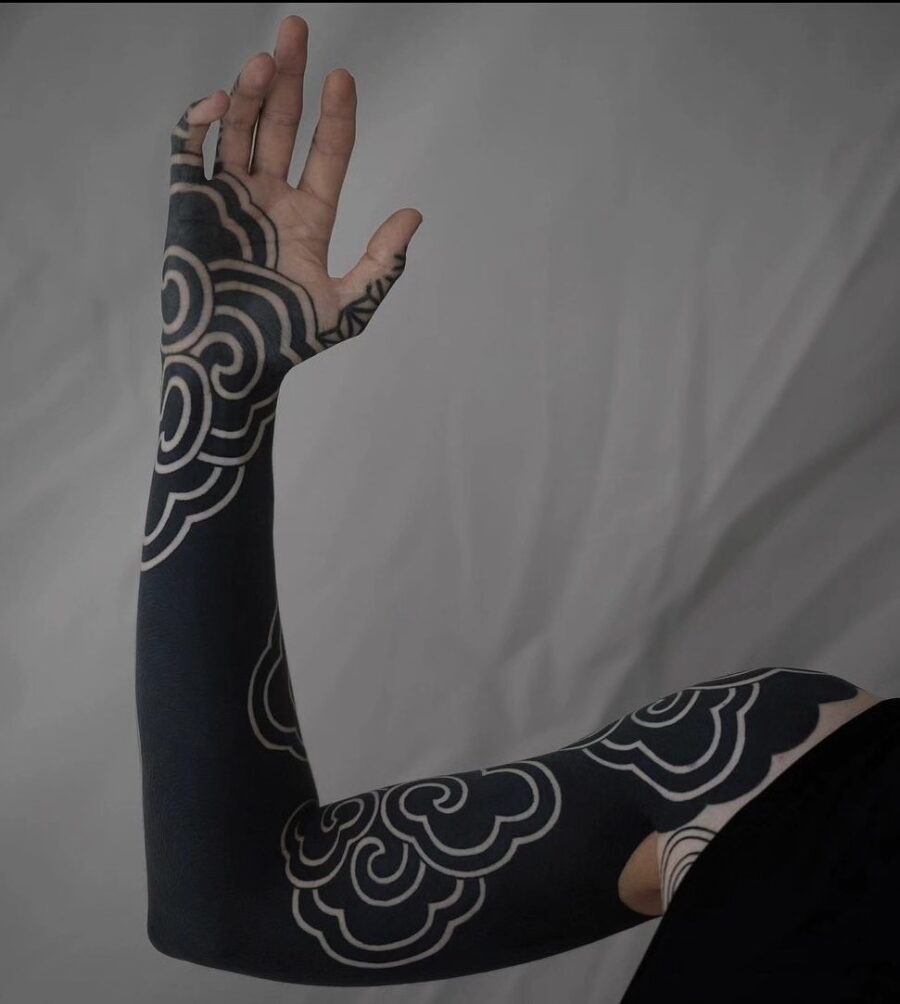 This black sleeve tattoo features intricate cloud patterns that flow elegantly along the arm.