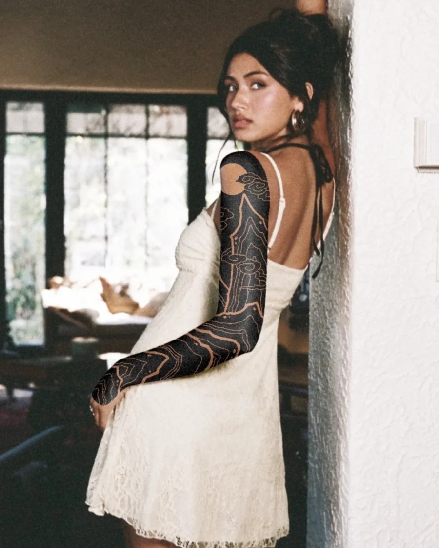 This striking black sleeve tattoo features intricate designs that elegantly wrap around the model's arm.