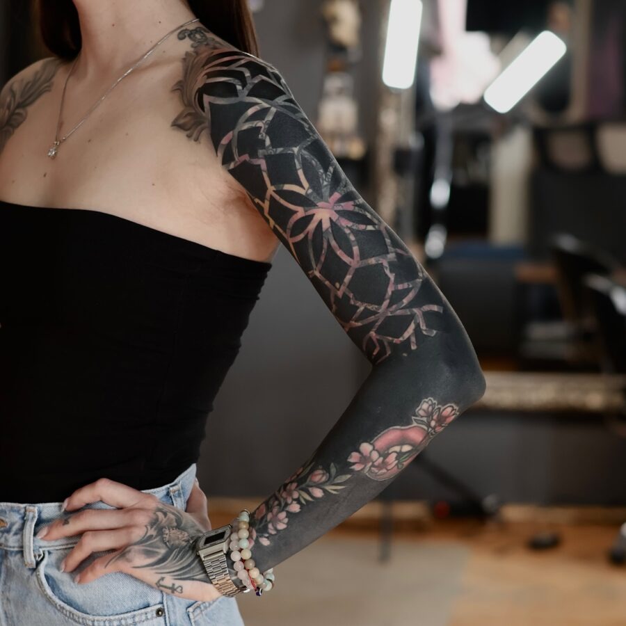 This tattoo features bold black ink intricately designed into floral patterns.