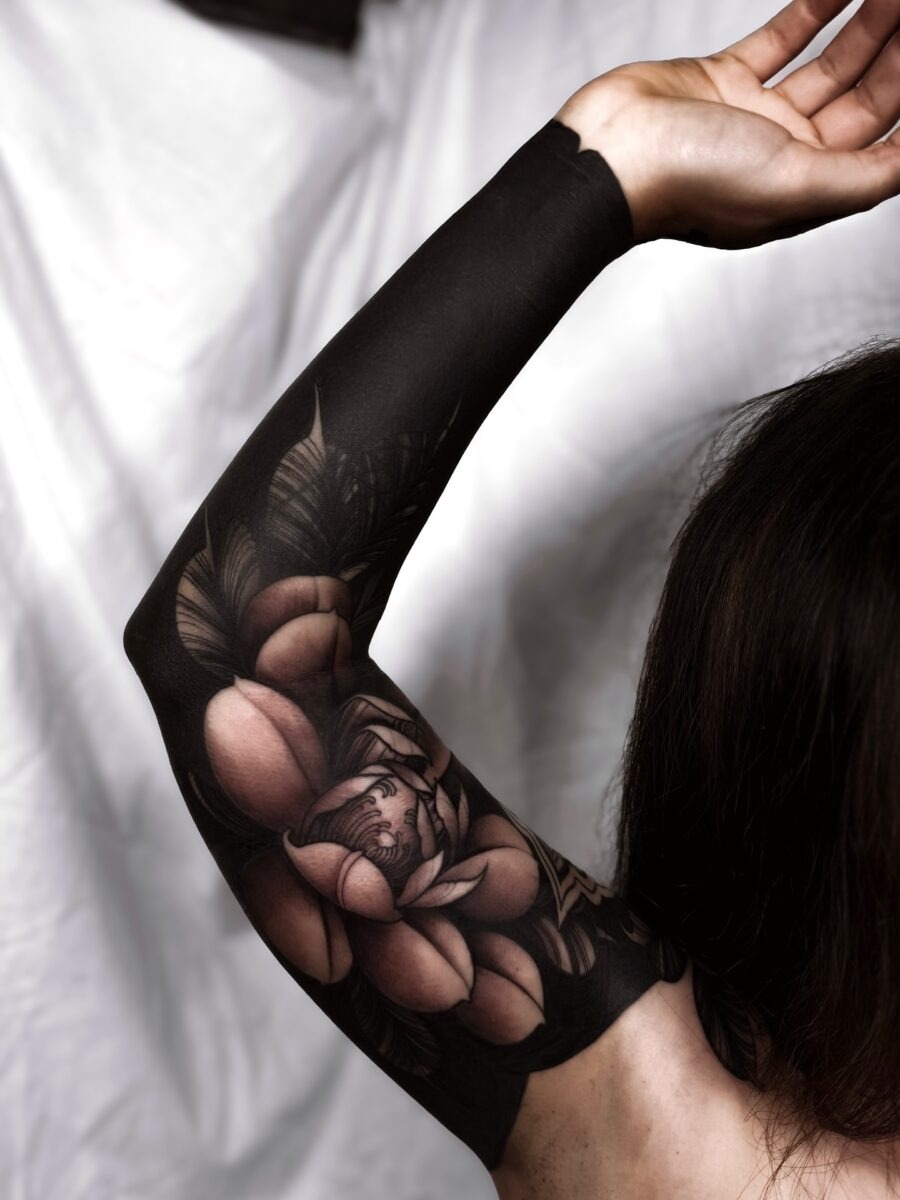 This tattoo features bold black ink intricately designed into floral patterns.