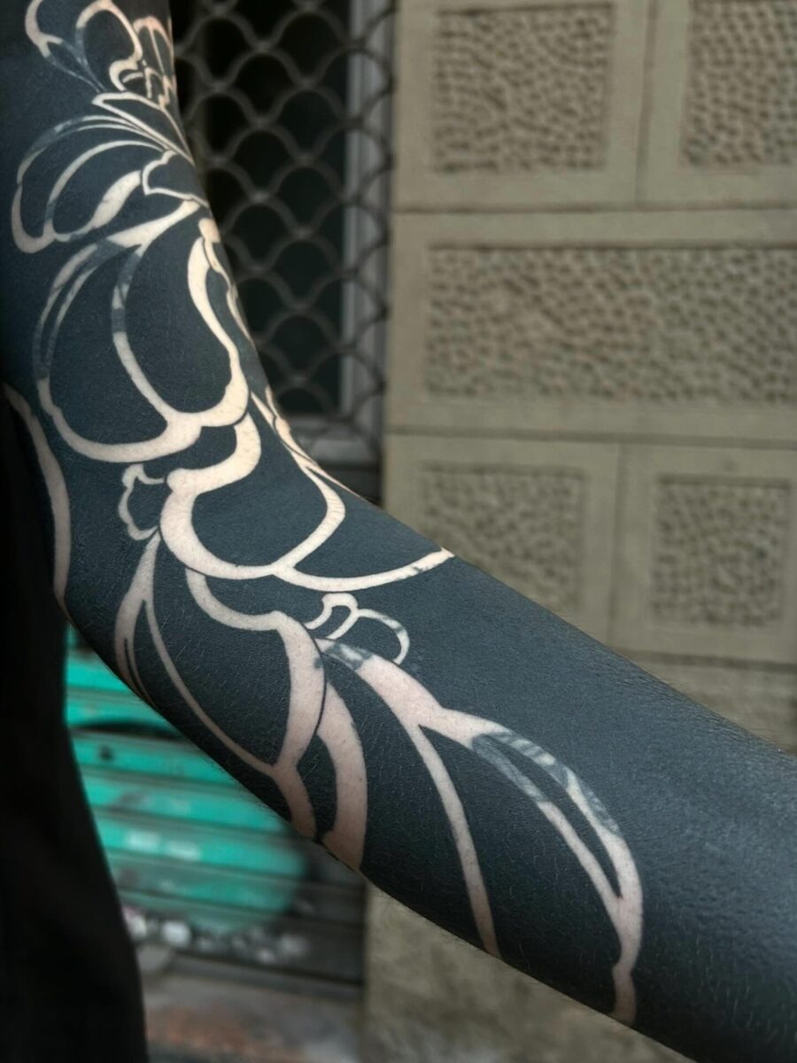 This tattoo features bold black ink intricately designed into floral patterns.