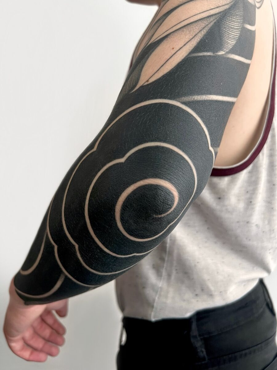 This tattoo features intricately designed swirling patterns in deep black ink.