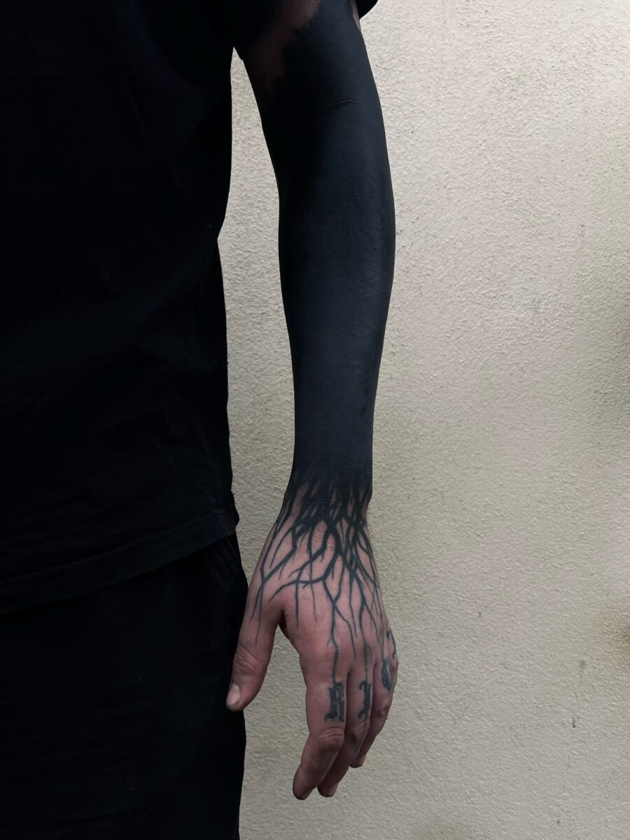 This striking black sleeve tattoo features intricate root designs that extend beautifully down the arm.