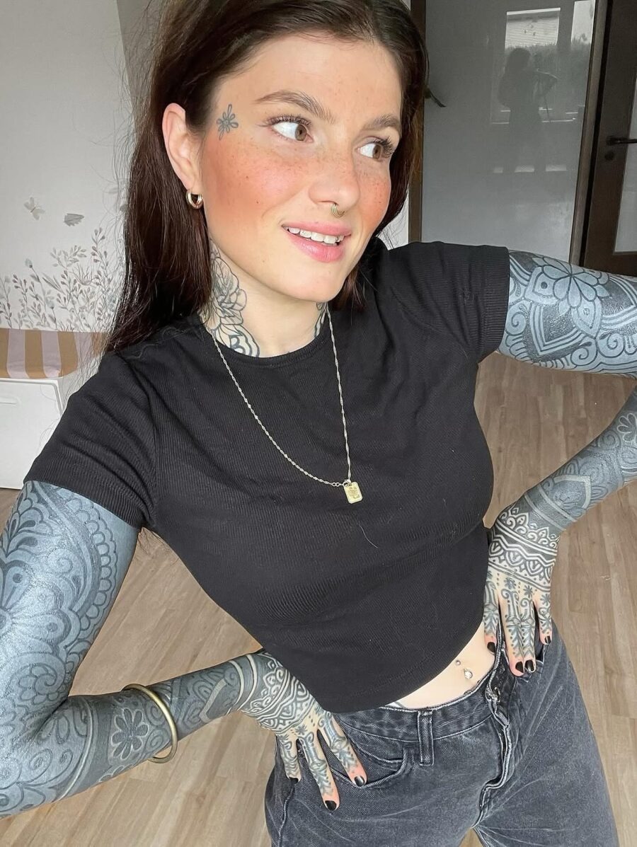 This image showcases a woman confidently flaunting her intricate black sleeve tattoos.