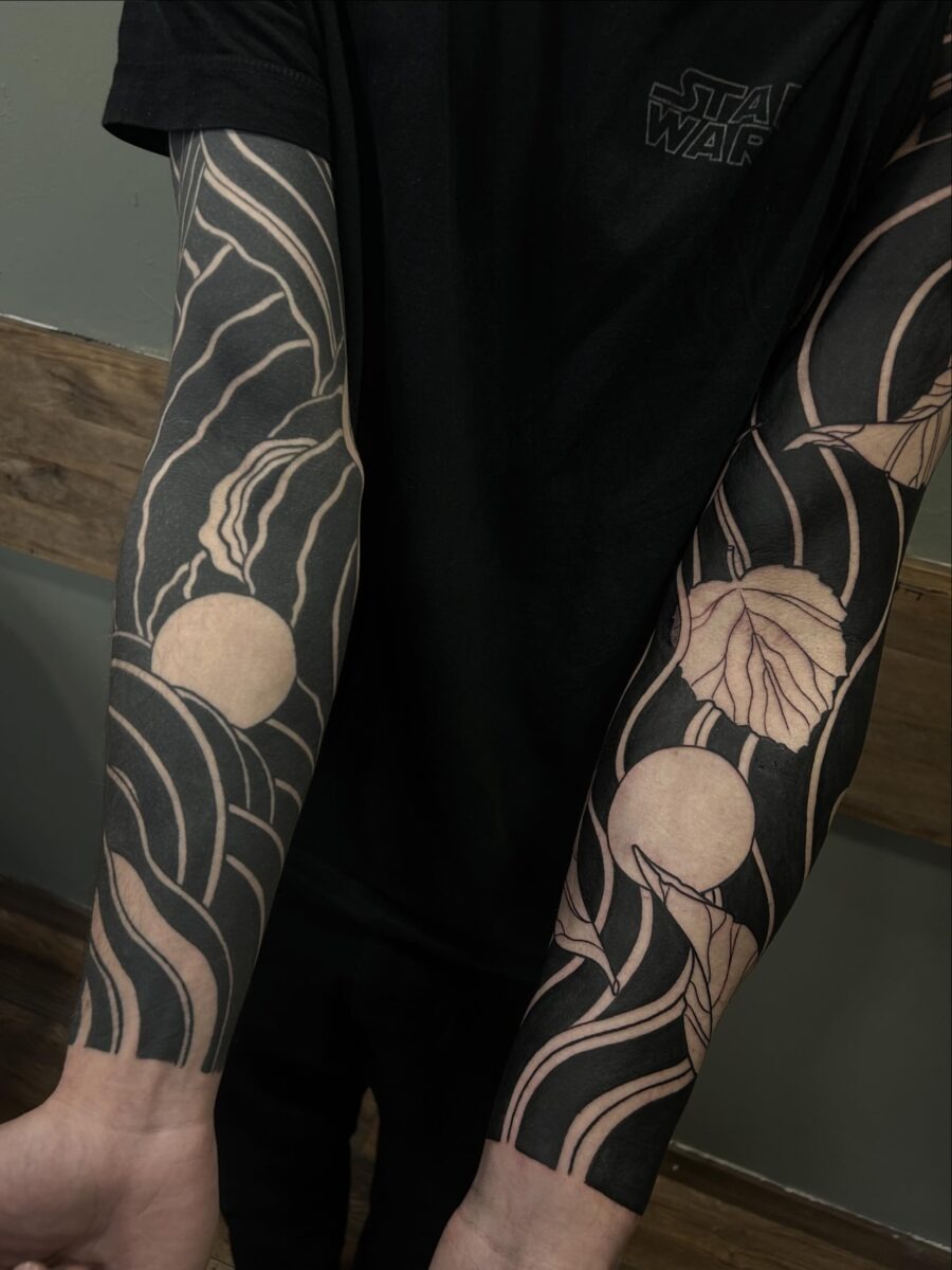 This striking black sleeve tattoo features intricate floral designs intertwined with bold lines.
