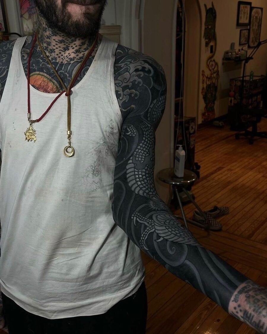 This stunning black sleeve tattoo features a detailed dragon intertwining with flowing cloud patterns.