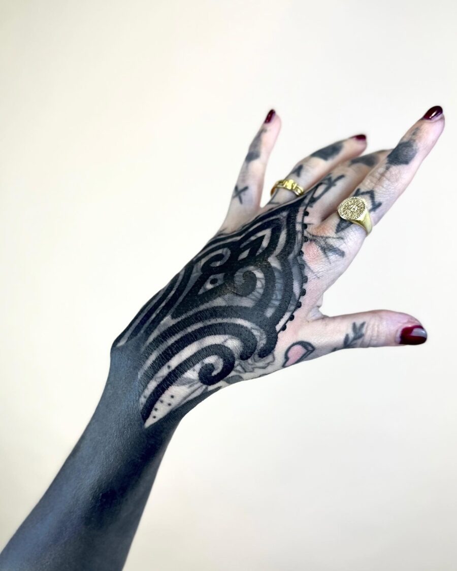 This black sleeve tattoo features intricate patterns that beautifully cover the hand.