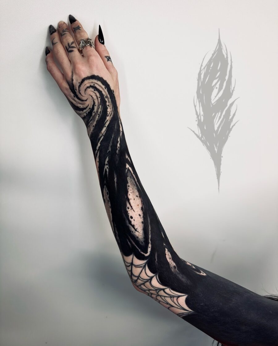 This black sleeve tattoo showcases a captivating swirl pattern that flows beautifully along the arm.
