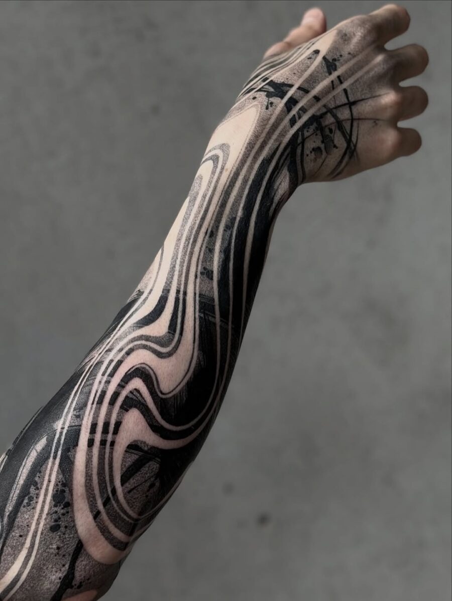 This black sleeve tattoo features a stunning array of wave-like patterns that flow elegantly around the arm.