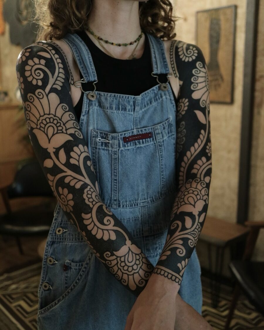 This tattoo features bold black ink intricately designed into floral patterns.