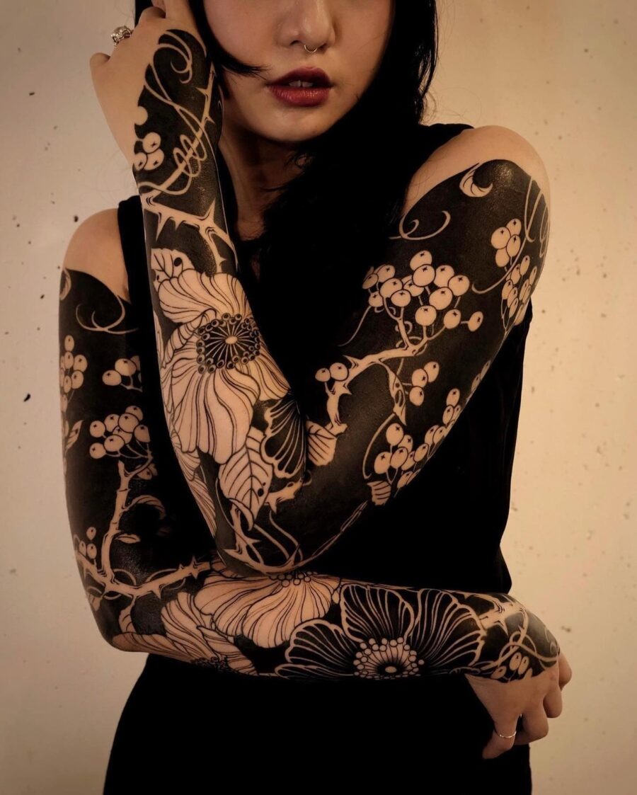 This striking tattoo features stunning floral patterns that wrap around both arms.