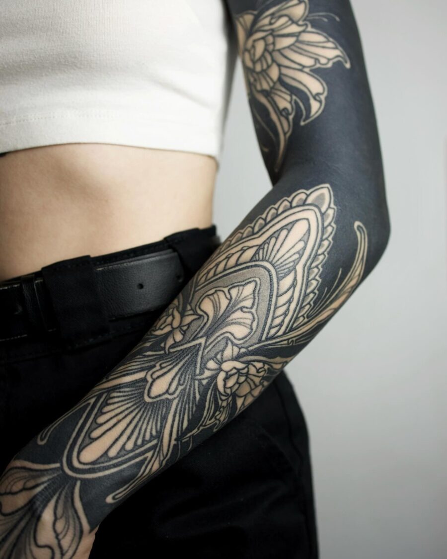 This black sleeve tattoo features stunning floral patterns that elegantly wrap around the arm.