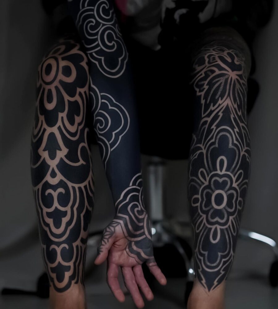 These black sleeve tattoos showcase intricate floral designs that flow beautifully across the skin.