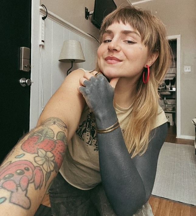 This image showcases a unique black sleeve tattoo that contrasts beautifully with colorful art on the other arm.