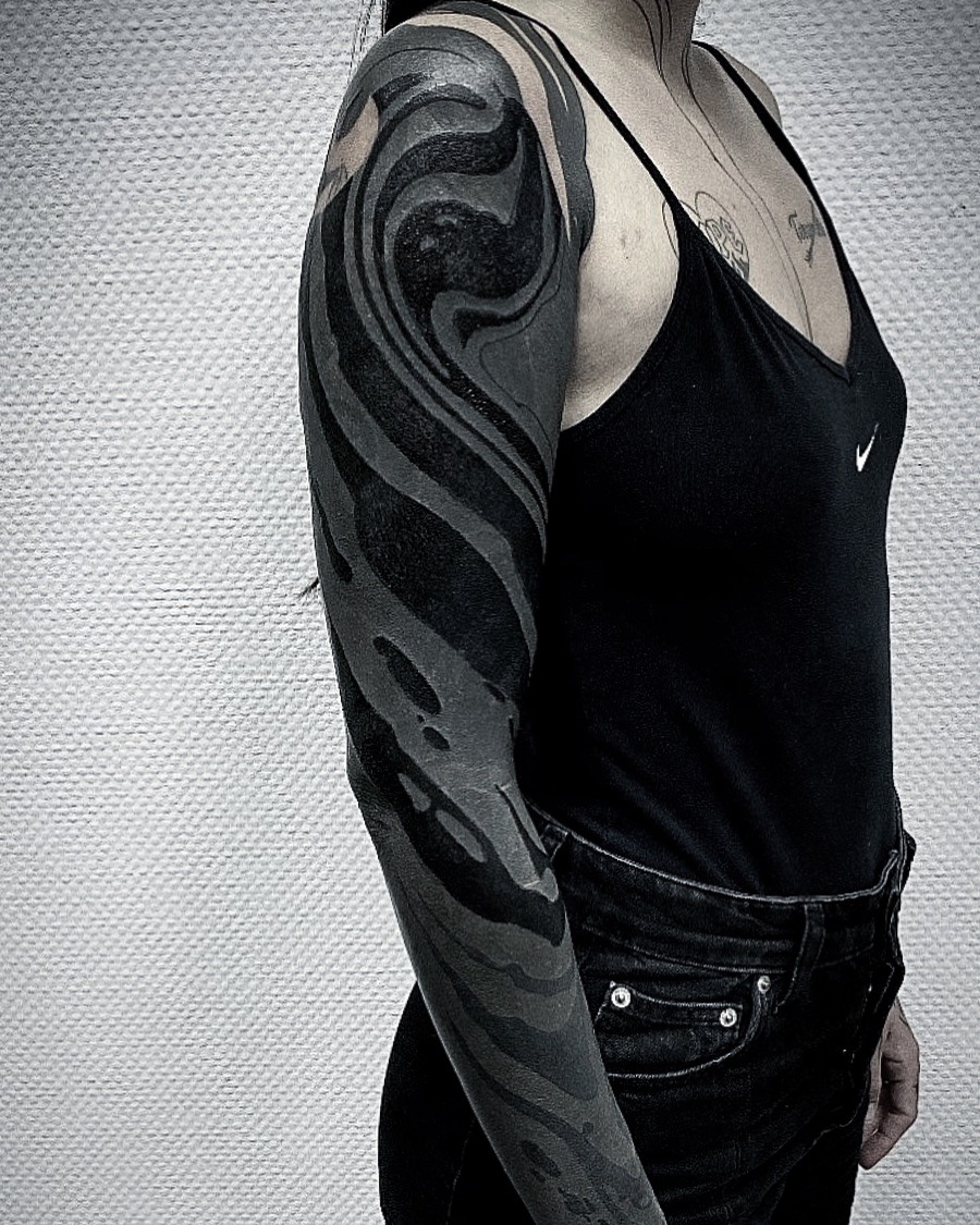 This black sleeve tattoo features mesmerizing swirling patterns that flow elegantly along the arm.