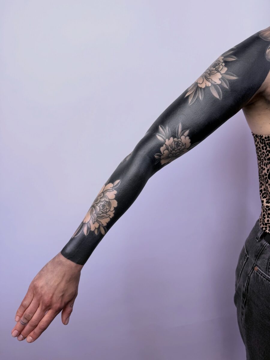This sleeve tattoo showcases intricate floral patterns in black ink.