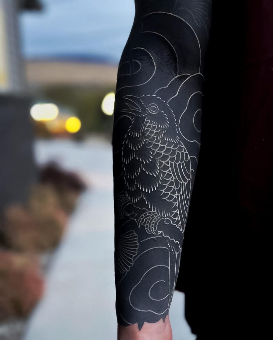 This striking black sleeve tattoo features a detailed bird perched among swirling clouds.