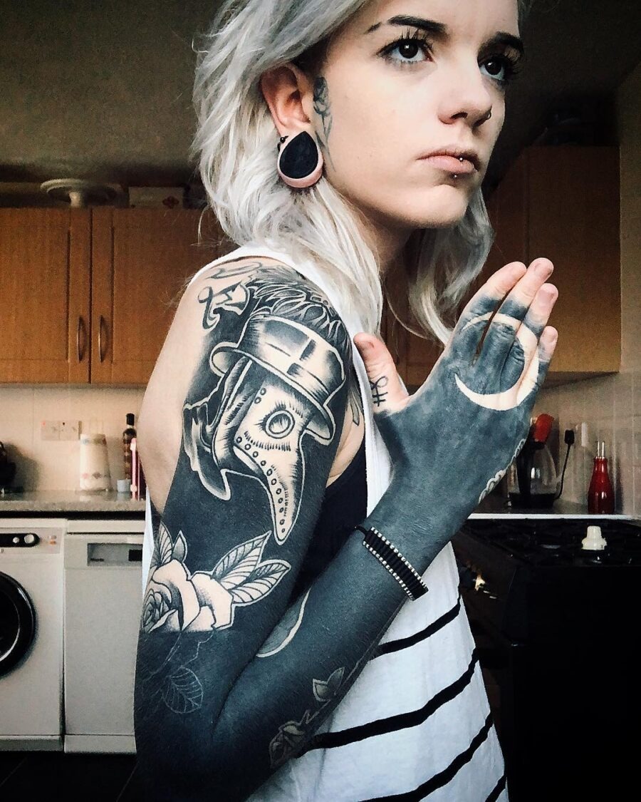 This striking black sleeve tattoo features intricate designs, showing a blend of gothic elements and nature.