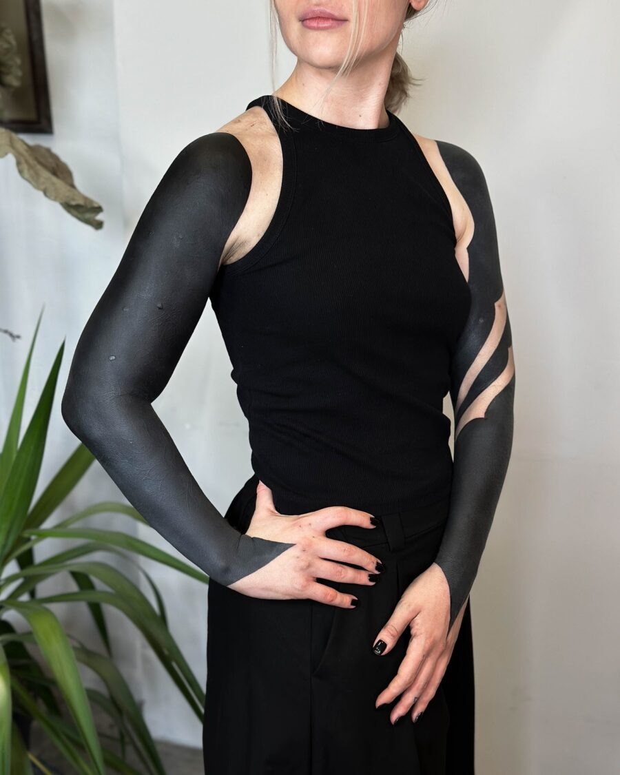 This image showcases a stunning black sleeve tattoo that features a blend of solid black and negative space designs.