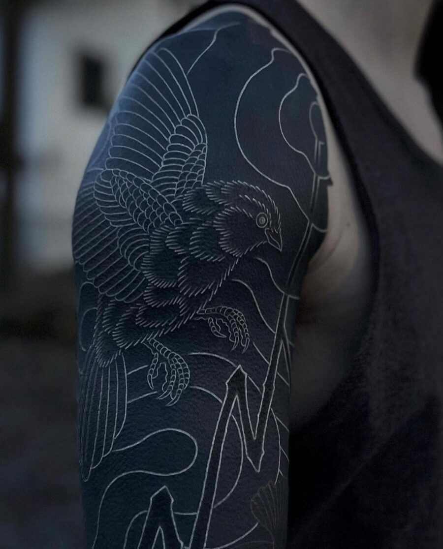 This striking black sleeve tattoo showcases a beautifully detailed bird in flight.