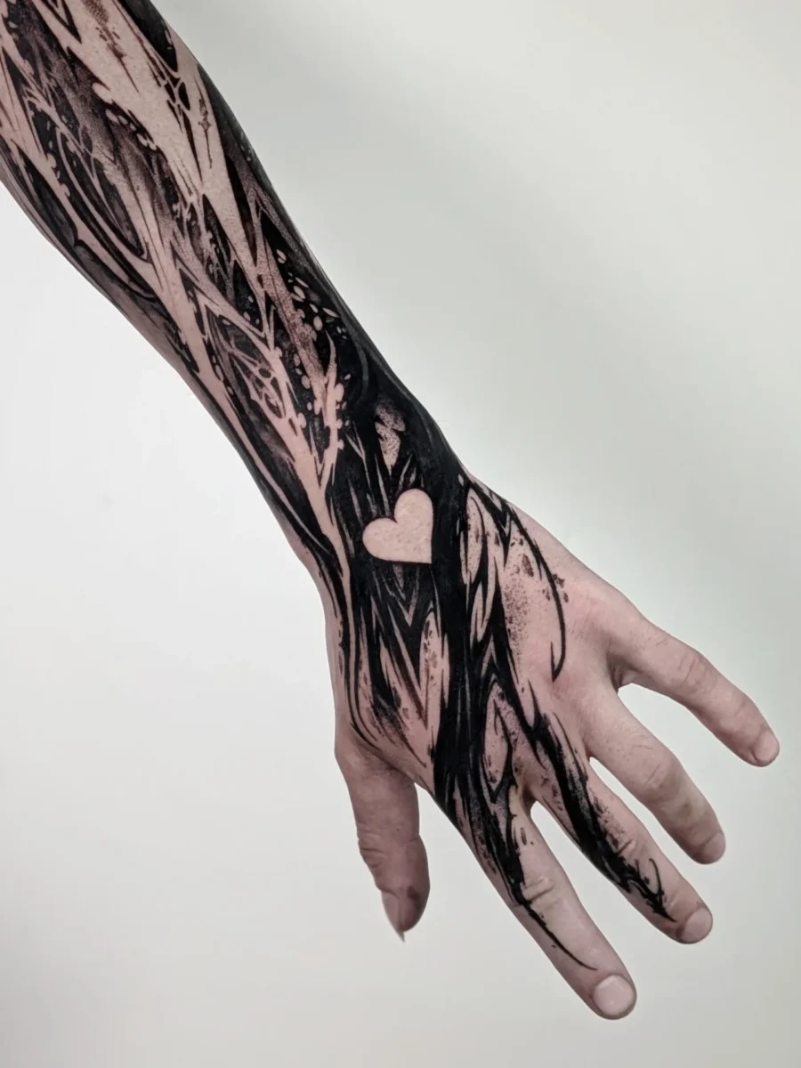This tattoo features striking black ink designs that blend abstract elements with a subtle heart.