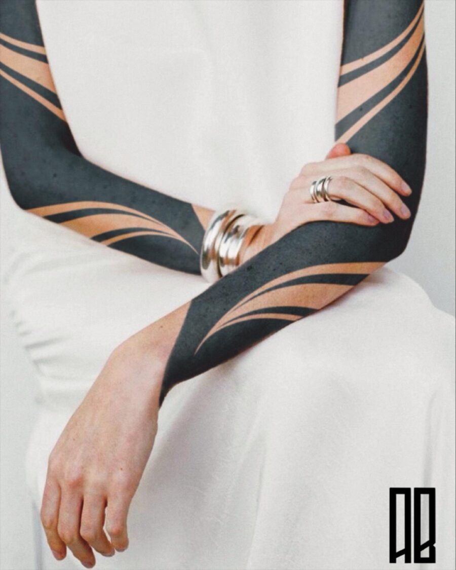 This sleek black sleeve tattoo features smooth, flowing lines that create a modern and artistic vibe.