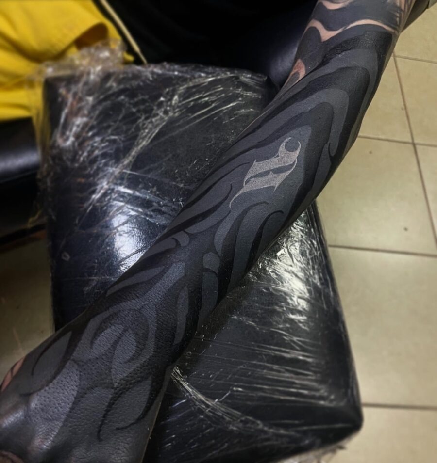This black sleeve tattoo features elegant wave patterns that flow seamlessly along the arm.