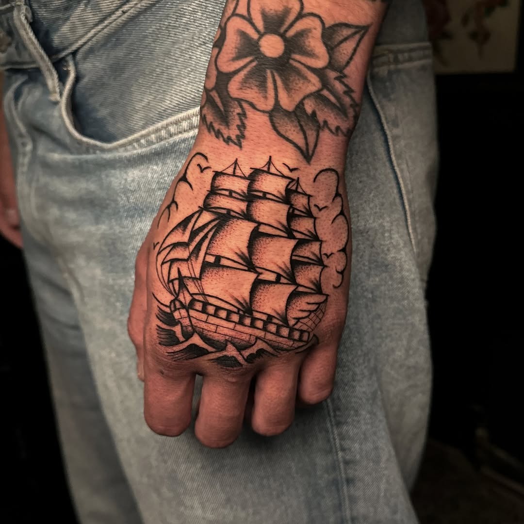Intricate ship tattoo on hand with floral design Tattoo Design